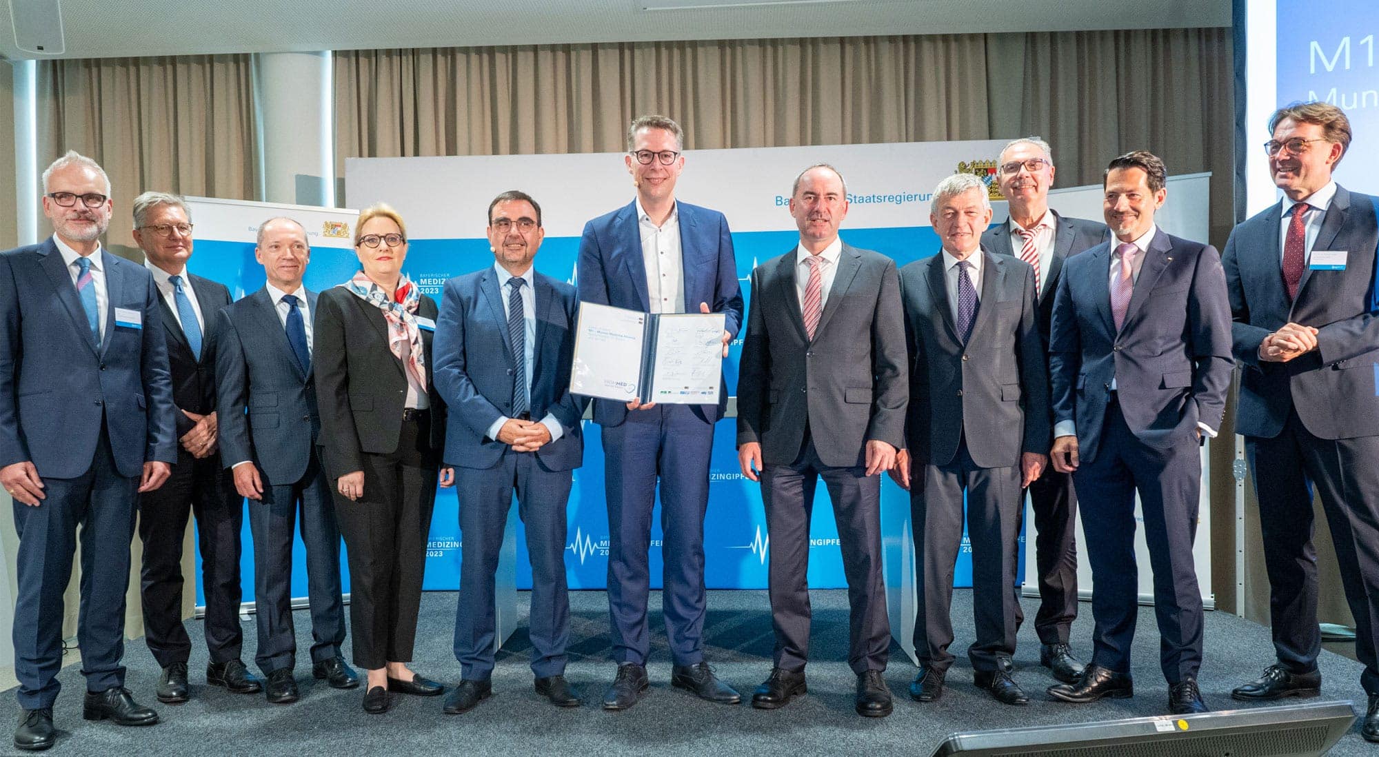 Die Unterzeichner des Letter of Intent zu M1 – Munich Medical Alliance beim Bayerischen Medizingipfel im Klinikum rechts der Isar mit Bayerns Wissenschaftsminister Markus Blume in der Mitte: Prof. Dr. Thomas Gudermann (1.v.l.), Dekan der Medizinischen Fakultät der LMU, und Prof. Dr. Markus M. Lerch (3.v.r.), Ärztlicher Direktor und Vorstandsvorsitzender des LMU Klinikums